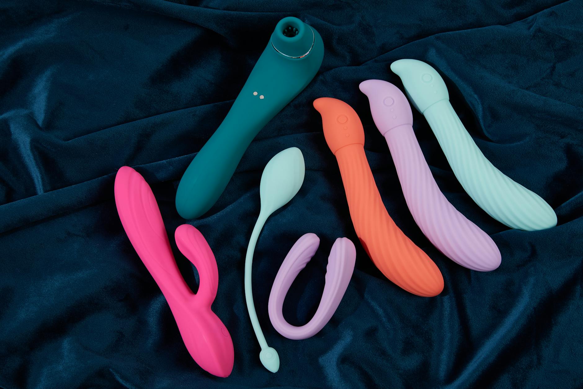 A yellow silicone vibrator surrounded by fresh fruit on a bright yellow background