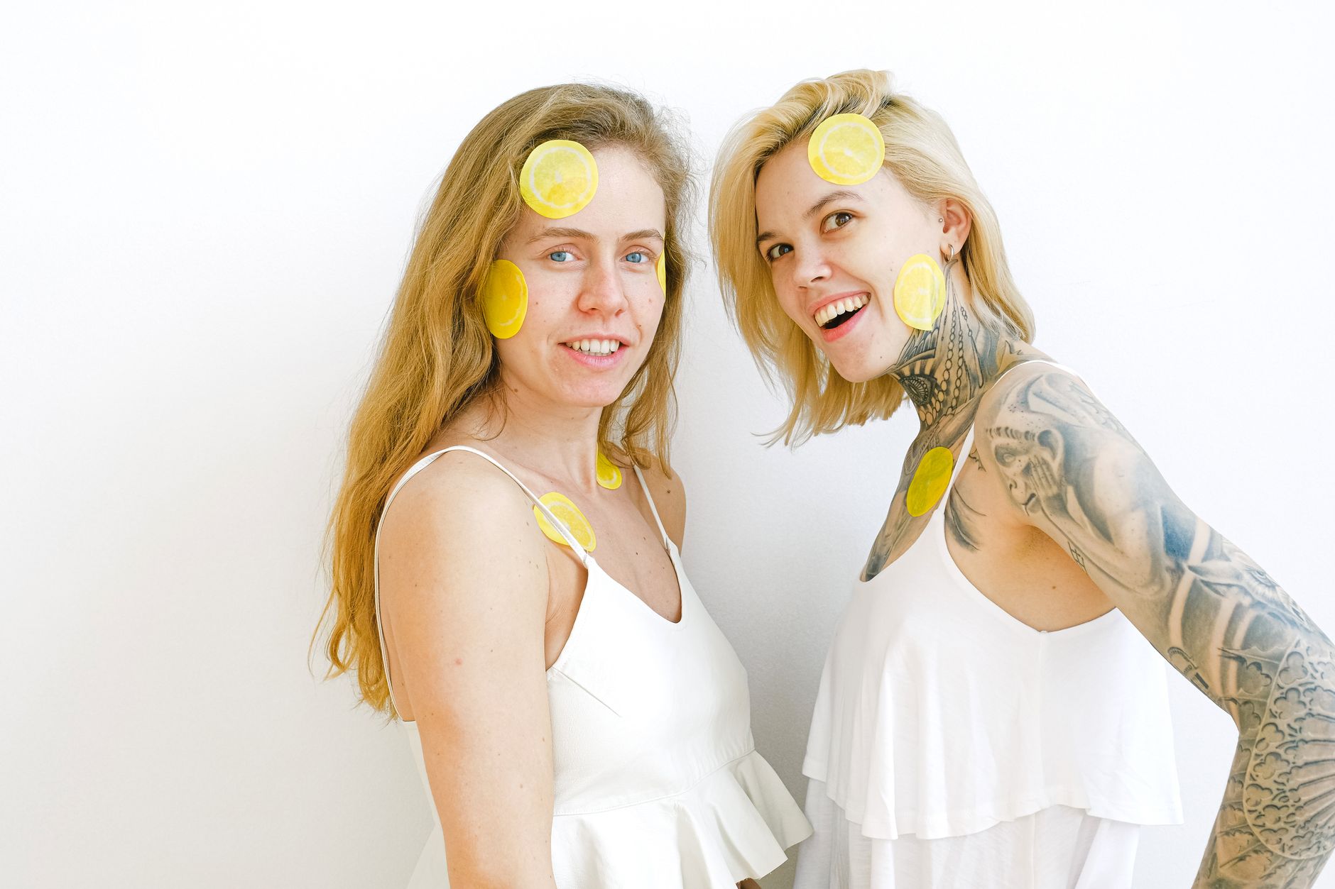 Two smiling women with lemon slices, expressing joy and fun indoors.
