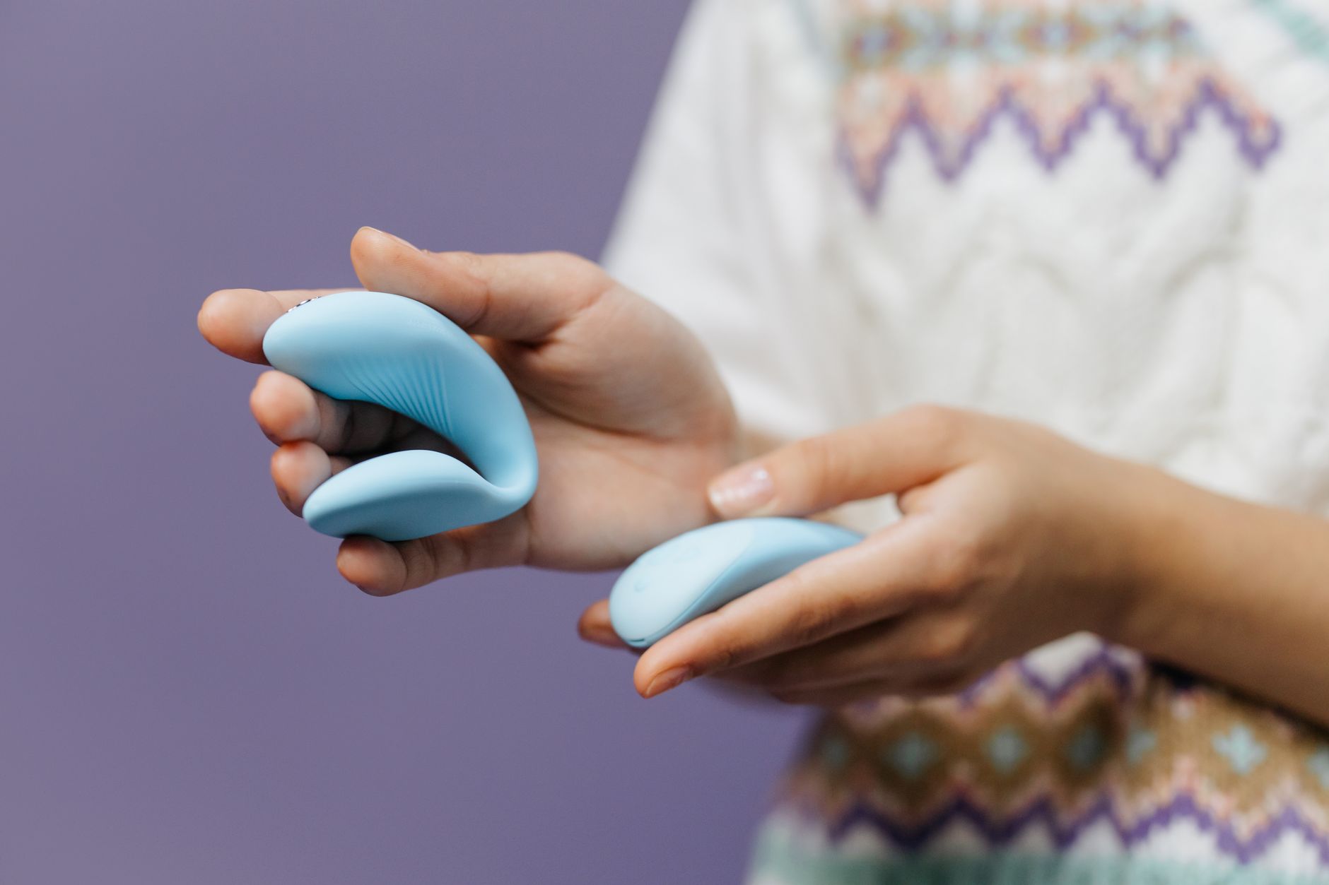 Close-up of hands holding a sleek blue lemon vibrator, representing accessible pleasure during medication use